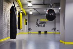 an empty gym with boxing gloves hanging from the ceiling and punching bags on the wall