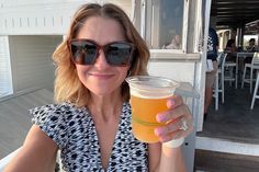 a woman in sunglasses holding up a drink