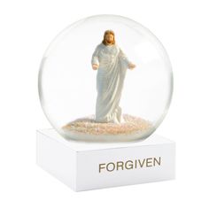 a snow globe with a statue of jesus in it and the words forgiven