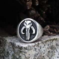 Our Mandalorian symbol-inspired Skull ring is a wonderfully realistic interpretation of the mysterious skull marking seen on the armor of iconic bounty hunter. There is a lot of speculation about the origin of the sigil on the ring. Some people states that the symbol is based on the skulls of ancient “Mythosaurs”, city Collectible Symbolic Skull Rings, Symbolic Skull Rings Collectible, Mandalorian Symbol, Witcher Wolf, Gothic Bracelet, Burning Desire, Viking Pendant, Viking Ring, Viking Bracelet