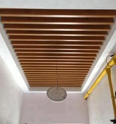 a ceiling with wooden slats in the middle and a light fixture hanging from it's side