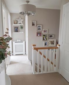 a room with pictures on the wall and stairs leading up to an upstairs landing area