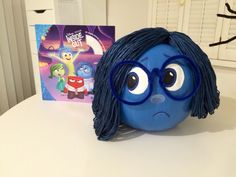 a blue toy with glasses on top of a table next to a book about inside out