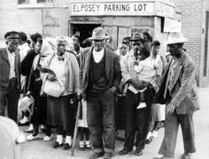 black and white photograph of people standing in front of a parking lot