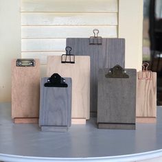 five wooden clipboards with clips attached to them sitting on a table in front of a window