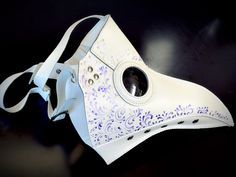 Travel back in time with our white plague doctor mask with purple filigree! Created with comfortable vegan leather, this mask is great for all-day wear and easy to breathe in. Look great and feel great with our fashionable plague masks! White/purple Color.

Age Group/Gender - Adult/Unisex
Size/Type - One size fits all adults
Mask Color - White
Filigree Color - Purple
Mask Material - Vegan Leather White Adjustable Masks And Prosthetics For Masquerade, Adjustable White Masks And Prosthetics For Masquerade, Plague Doctor Cosplay, Beak Mask, Plague Doctor Costume, Plague Mask, Plague Doctor Mask, Thank You Wishes, Doctor Costume