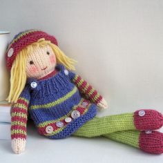 a knitted doll sitting next to a stack of books