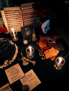 a table topped with cards and candles on top of a black cloth covered tablecloth