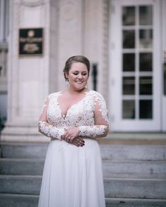 a woman in a white dress standing on some steps with her arms folded over her chest