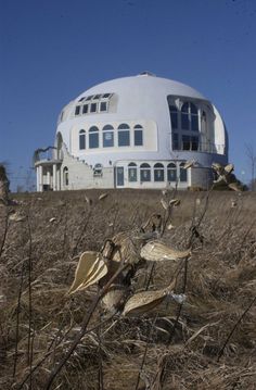 a large white building sitting on top of a dry grass field