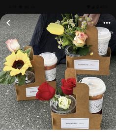 three boxes with flowers in them sitting on the ground next to a person's legs