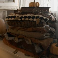 a stack of blankets and pumpkins sitting on top of a window sill