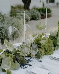 the table is set with wine glasses, grapes and other items for an elegant dinner