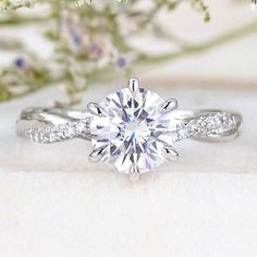 a white gold engagement ring with a twisted band and a round diamond center surrounded by flowers