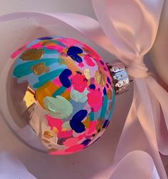 a colorful ornament with a pink ribbon around it