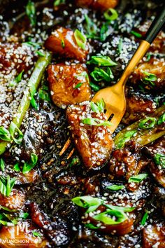 meat and vegetables are being cooked in a skillet with sesame seeds on the side