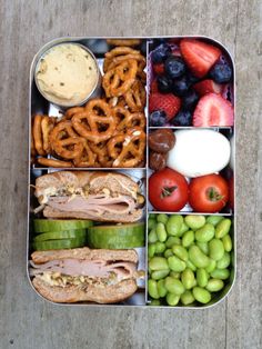 a bento box filled with fruits, vegetables and pretzels