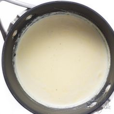 a pot filled with liquid sitting on top of a white counter next to a spoon