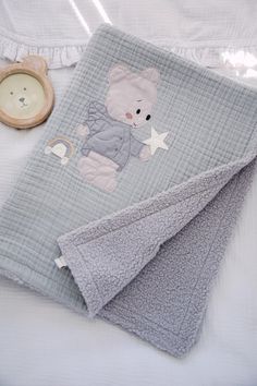 a baby blanket with a teddy bear on it next to a wooden toy and other items