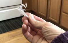 a person holding a toothbrush in their hand near a stove top oven and cabinets