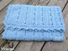 a blue knitted blanket sitting on top of a wooden floor