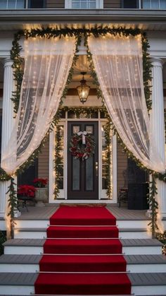 red carpeted steps leading up to a front door decorated with christmas lights and garlands