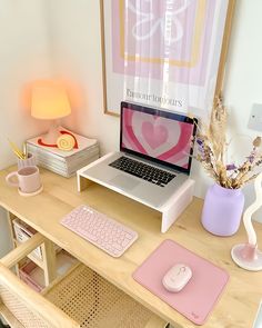 a laptop computer sitting on top of a wooden desk next to a pink mouse pad