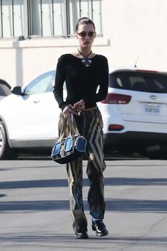 a woman is walking down the street with her hand in her pocket and holding a purse