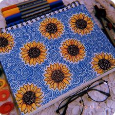 a notebook with sunflowers on it next to some markers and crayons