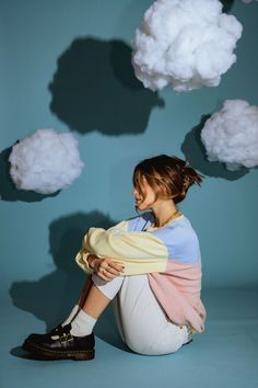 a woman sitting on the ground in front of clouds