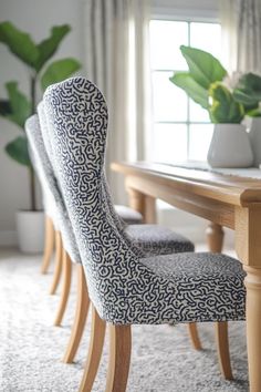 a dining room table with two chairs and a potted plant