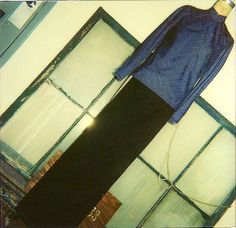 a blue shirt and black pants are on the floor next to some glass windows in a room