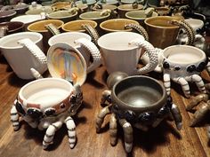 many cups and saucers are sitting on a table with octopus legs in front of them