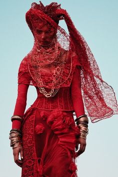 a woman in an elaborate dress and headdress is standing with her hands on her hips