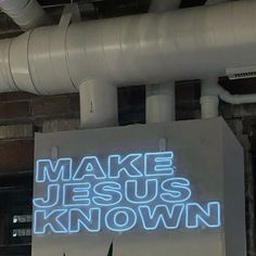 a sign that says make jesus known in blue neon lights on the side of a building