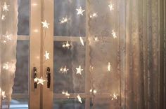 an open window with white stars on the curtain and light coming from it's side