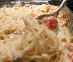 a spoon full of pasta and sauce in a casserole dish