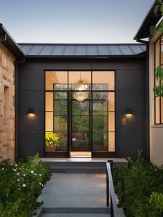 the entrance to a modern home with glass doors and stone steps leading up to it