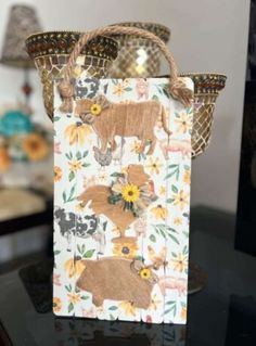 a paper bag with animals on it sitting on a table next to a vase and lamp