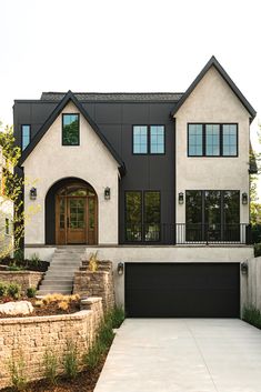 a large white and black house with two garages on the side of it's driveway