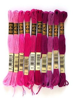 six skeins of pink and purple yarn lined up on top of each other