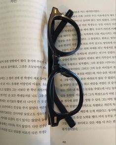 a pair of black glasses sitting on top of an open book with chinese characters in the background