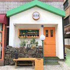 a small white and orange building with a green roof