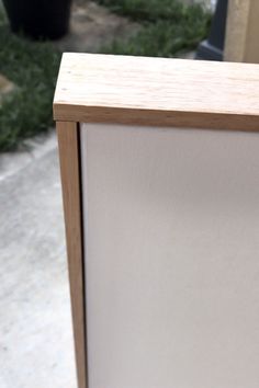 a white refrigerator sitting on top of a sidewalk next to a potted green plant