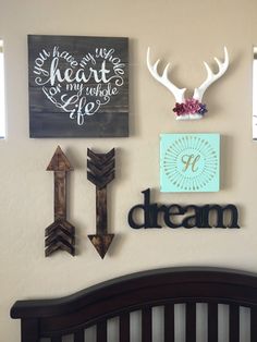 the wall above the crib is decorated with antlers, arrows, and signs