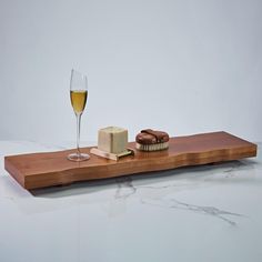 a wine glass and some cookies on a wooden tray