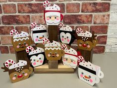 a group of paper cutouts with santa claus and reindeer faces on them in front of a brick wall