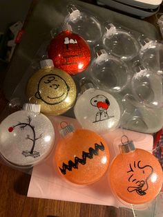 christmas ornaments are sitting on top of a piece of paper and some plastic balls with faces drawn on them