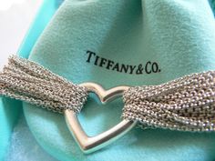 Feel like making a statement with your jewelry? Here's one that fits the bill wonderfully. Offered for sale is a gorgeous Tiffany and Co. Multi Strand Heart Mesh necklace. It is the perfect piece to wear when you want to make a classy and elegant statement. The necklace is composed of twenty strands of chain linked together by a solid silver heart. A design that only Tiffany can come up with! Wonderful and very contemporary piece that fits a lifestyle on the go -- this necklace can be worn to al Tiffany Graduated Chain Link, Infinity Chain Necklace Tiffany Co, Tiffany And Co Blue Heart Necklace, Elegant Chain Necklace For Valentine's Day, Elegant Valentine's Day Necklace With Chain, Elegant Valentine's Day Chain Necklace, Luxury Heart Charm Jewelry For Formal Occasions, Luxury Formal Jewelry With Heart Charm, Luxury Heart Shaped Jewelry For Evening