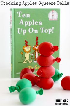 the stacking apples squeezee balls are on top of each other in front of a book